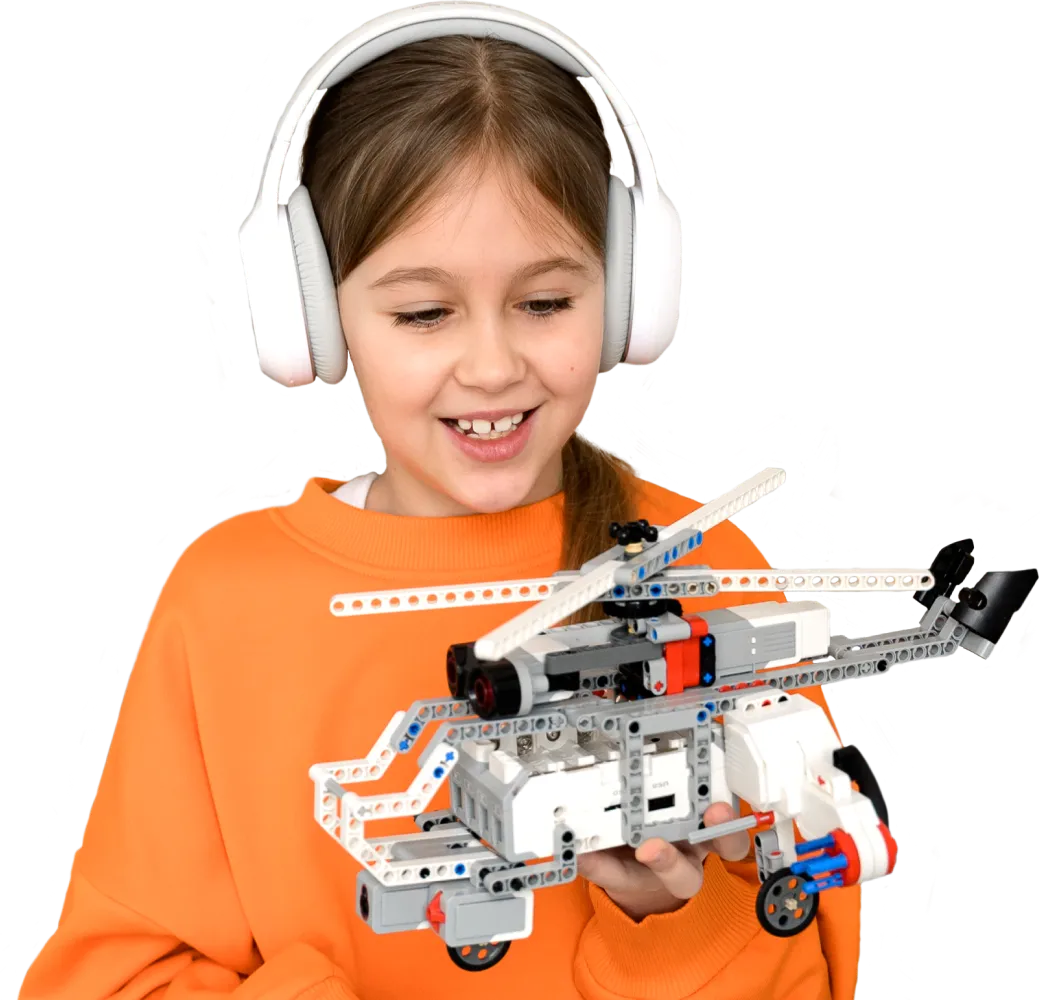 Девочка с наушниками держит вертолёт из LEGO в Лиге Роботов на уроке робототехники для детей