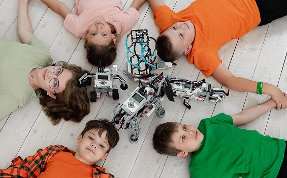 Пятеро детей лежат кругом на полу вокруг собранных роботов LEGO Mindstorms в классе Лиги Роботов, Екатеринбург